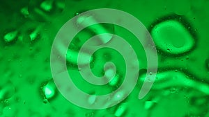 Green colored water surface moving waves with oil bubbles under ultra sound vibrations, abstract background template.