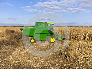 Green combine threshes corn in the field