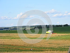 Green combine tractor harvesting oast field