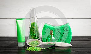 Green composition beauty treatment products in green colors: shampoo, soap, bath salt, oil.