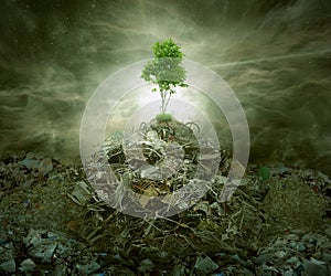 Green concept as tree on top mountain heap of garbage