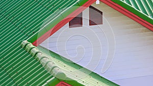 Green concrete tile polygonal roof and white wooden gable combination with 2 attic window of vintage house