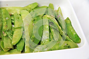 Green cooked stir-fried vegetable snow peas bean on square rectangular plate