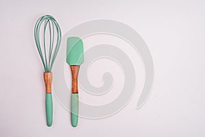 Green cooking whisk and a spatula isolated on a white background