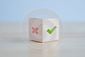 Green correct check mark and red wrong or cross icon on wooden block for true or false.