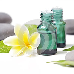 Green cosmetic bottles with zen stones and frangipani flower