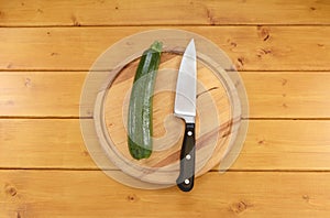 Green courgette with a knife on a chopping board