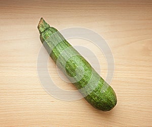 A green courgette or zucchini on a wooden table