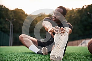 On the green court. Young black man is with basketball ball outdoors