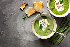 Green cream asparagus soup with crispy toasts on a gray background. Vegan and vegetarian lunch and dinner. Top view, copy space