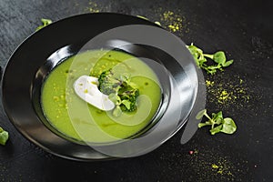 Green cream soup from broccoli on black background