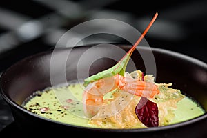 Green Cream Soup with Shrimp . Thai food Shrimp green curry in a dark plate on a black background