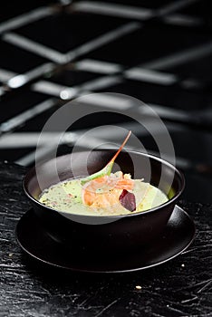 Green Cream Soup with Shrimp . Thai food Shrimp green curry in a dark plate on a black background