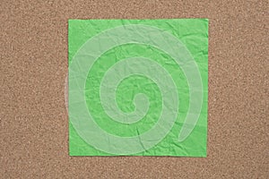 Green creased paper note on cork background