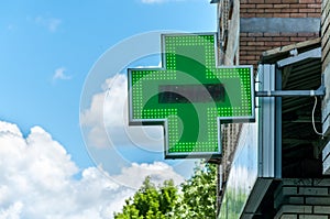 Green cross pharmacy sign or symbol on the building facade view from the street