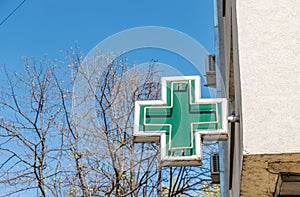 Green cross pharmacy sign or symbol on the building facade view from the street