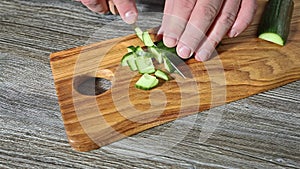 Green cucumber cutting on wooden chopping board  very close up view