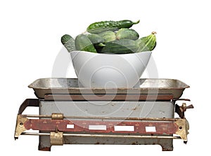 Green cucumbers in a white cup on old mechanical scales isolated