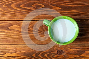 Green cup of milk on a vintage wooden background. Flat top view. Green mug with milk