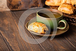 Green cup of tea with mini chocolate bun