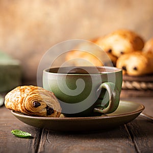 Green cup of tea with mini chocolate bun