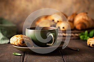 Green cup of tea with mini chocolate bun