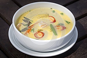 Green curry creamy soup with coconut milk, shrimp, red pepper, bean in white bowl, Thai cuisine