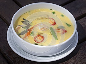 Green curry creamy soup with coconut milk, shrimp, red pepper, bean in white bowl, Thai cuisine