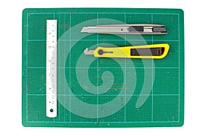 Green cutting mats with iron ruler and cuter on white background