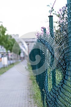 Green damaged wire-mesh fence is ruined after collision with car accident as crushed fence car insurance and property insurance