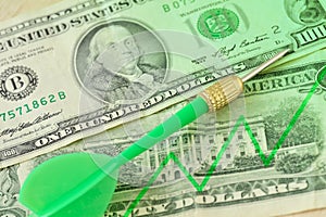 Green dart and graphic with ascending line on dollar banknotes - Concept of increasing money value