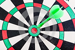 Green dart hit exactly the target of the dartboard, goal achievement, game play. The concept of success.