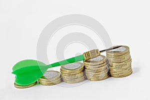 Green dart on raising coin stacks - Money growth concept