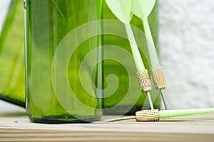 Green darts from a dartboard resting on beer bottles