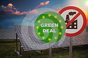 Green deal sign in front of photovoltaic panels. Renewable and alternative power generation. Ecology concept.