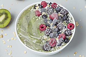 Green detox smoothie bowl with kiwi, bananas, granola and frozen berries. Healthy Breakfast.