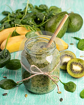 Green detox smoothie in a glass jar with banana, kiwi, spinach