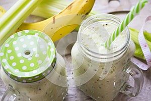 Green detox smoothie in glass jars on wooden table