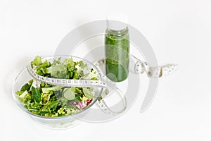 Green detox smoothies, vegetables salad in glass bowl, tailor measuring tape isolated on white background. Proper