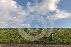 Green dike with blue sky and white coulds