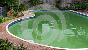 Green dirty pool algae water in a suburban backyard