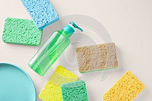 Green dish washing soap with cleaning sponge on light beige background