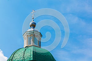Green dome of a Christian temple with a silver cross against the