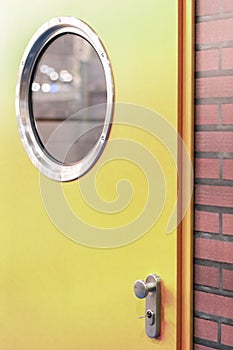 A green door with a round window in a brick wall