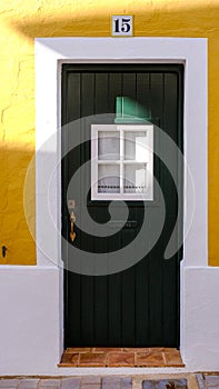 green door with white and yellow wall. number 15