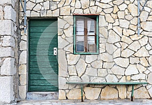 The green door, a window and a bench on the wall of sandstone photo
