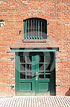 Green door and window in brick wall