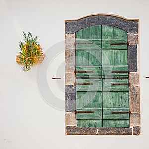 Green doors with flowers in the pot on a white wall