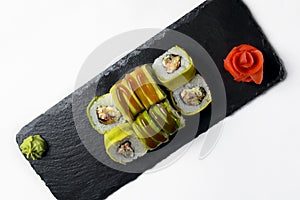 Green dragon sushi rolls on the white background. Served on a black tray. Traditional Japanese cuisine