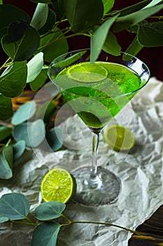 A green drink with ice cubes in a glass for mojito on crumpled w
